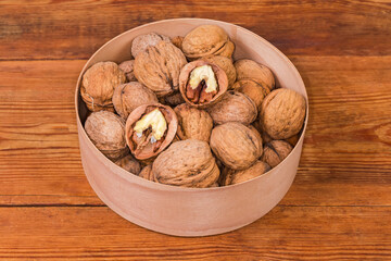 Walnuts in shells in wooden round box on rustic table