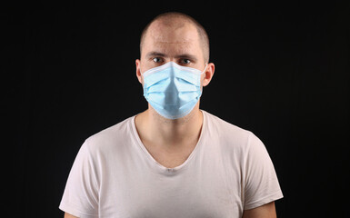 Young man with medical mask on black background