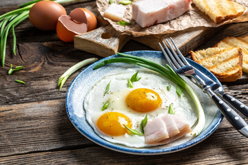 Fried eggs with lard bacon on the wooden table, Traditional Ukrainian or belorussian food, Food recipe background. Close up