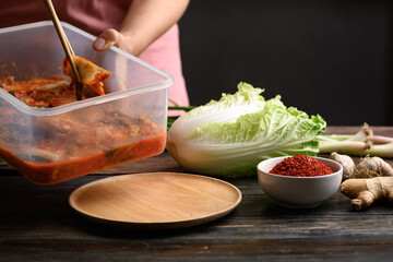Woman hand picking kimchi cabbage by chopsticks on wooden plate for eating, Homemade Korean food