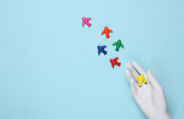 Mannequin hand with Many colored toy airplanes on blue background.