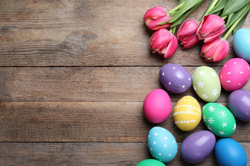 Obraz na płótnie Canvas Colorful eggs and tulips on wooden background, flat lay with space for text. Happy Easter