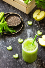 Food and drink, healthy diet and nutrition, vegan, vegetarian concept. Green smoothie with celery and apple on a dark stone countertop.
