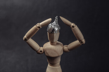 Wooden puppet with foil hat on black background. Conspiracy