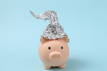 Piggy bank with foil hat on blue background