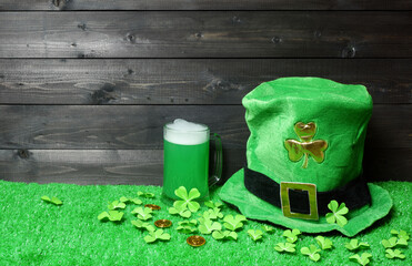 Mug of green beer and leprehaun cap, clover leaves and coins on green grass, dark wooden planks background. Saint Patricks Day banner, poster, flyer, invitation template