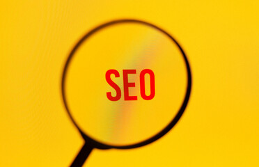 Word seo on yellow screen through magnifying glass.