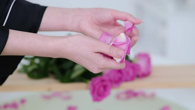 female hands pour rose petals into the bath. Luxury White Marble Bathroom Flowing Water to the Bath with pink Rose. Romantic weekend in a hotel. Slow motion video. High quality 4k stock footage.