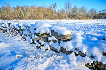 stonewall covered in snow near agriculture field