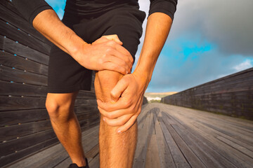 Man runner holding his painful knee because of injury. Injury from workout and exercising