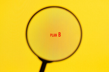 Text plan B plan on yellow screen through magnifying glass. Business, strategy