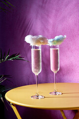 champagne in a glass decorated with a cloud on a pink background.
