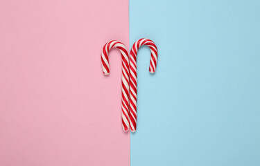 Christmas striped candy canes on a blue pink background.