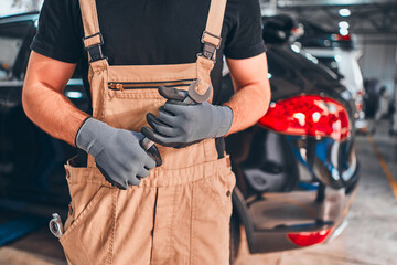 Hand of car mechanic with wrench. Auto repair garage.