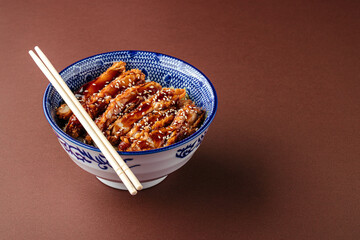 Katsudon fried chicken with rice in a bowl on the brown background