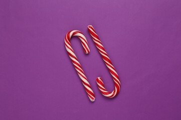 Christmas striped candy canes on purple background.