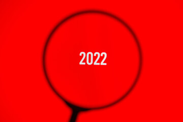2022 on red screen through magnifying glass.
