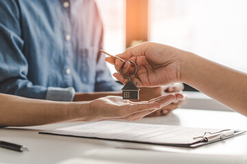 Realtor agent giving a key of apartment to new owner after signed lease agreement.