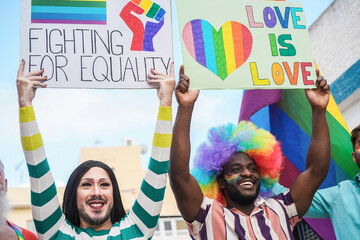 Multiracial gay people marching at LGBT pride parade with banners - Focus on drag queen face