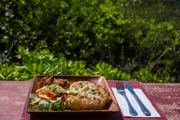 vegan cauliflower steak served outside on a wooden plate with green salad and sauteed potatoes