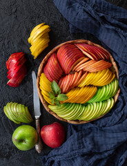 apple pie made of apples of three colors on a dark background, top view