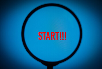 Text start!!! on blue screen through magnifying glass.