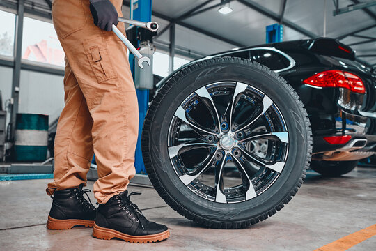 Mechanic holding a tire at the repair garage. Replacement of winter and summer tires.