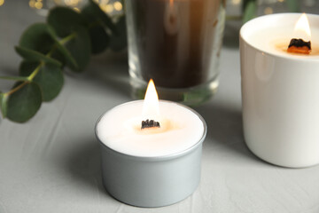 Fototapeta na wymiar Burning scented candles on light grey table