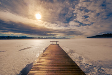 Barred wooden nose-piece on frozen lake in Upper Bavaria with Alps in background in winter with snow