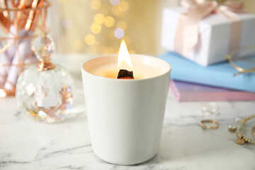 Burning candle with wooden wick on white table