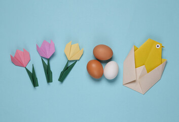 Origami chicken, eggs and tulips on blue background. Spring, easter concept