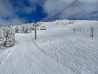 POV: Chairlift ride over vast ski resort slopes covered in pristine crud snow.
