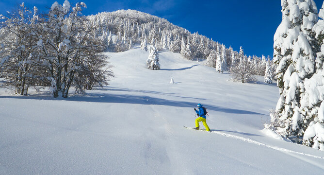 AERIAL: Man hikes in the pristine white countryside to splitboard off piste.
