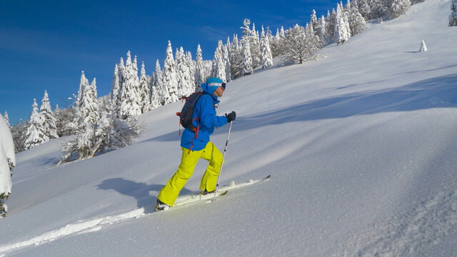 CLOSE UP: male tourist ski touring in the Julian Alps hikes up a snowy hill.