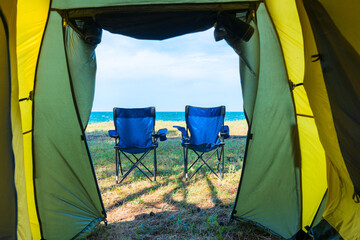 sea view and chairs from the camping tent - concept vacation, camping, relaxation