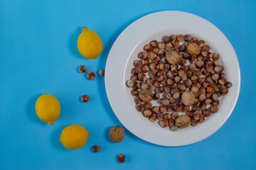lemons and hazelnuts lie on a white plate blue background
