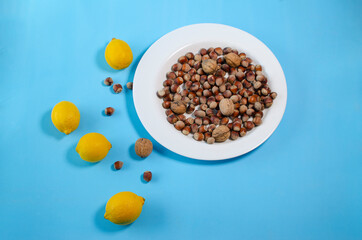 lemons and hazelnuts lie on a white plate blue background