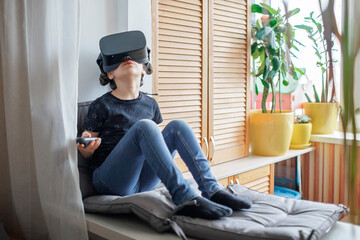 Cute girl wearing virtual reality googles at home, remote education experiment, future today, new...