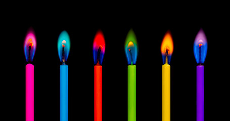 Six colorful burning candles light on the black background