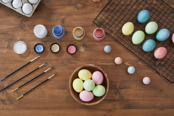 Top view background of pastel colored Easter eggs on wooden table and art supplies, DIY Easter decorations, copy space