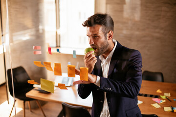 Businessman in conference room use sticky notes on glass wall. Handsome businessman making a business plan.