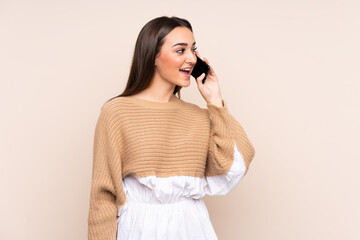 Fototapeta premium Young caucasian woman isolated on beige background keeping a conversation with the mobile phone