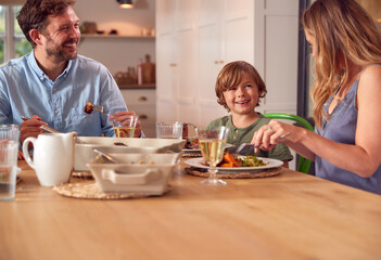 Family Sitting Around Table At Home Enjoying Meal Together