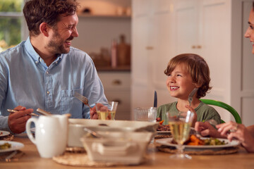 Family Sitting Around Table At Home Enjoying Meal Together