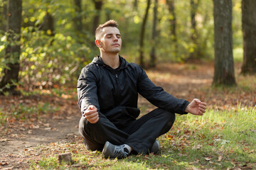 Naklejka na ściany i meble Sport man meditates in the lotus position in the autumn forest.