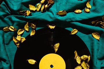 Layout of LP vinyl record on a cyan silk or saten fabric with yellow rose patels on it.  Old vintage record.