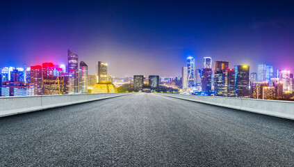 Asphalt road and modern city skyline with buildings in Hangzhou at night.