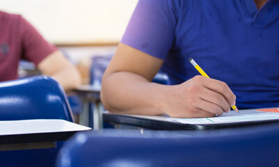 high school,university student study.hands holding pencil writing paper answer sheet.sitting lecture chair taking final exam attending in examination classroom.concept scholarship for education abroad