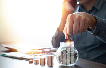 Man hand putting coins in glass bottle bank with money stack step up, economic growth diagram graph chart. Saving money for future plan, retirement fund. Business investment-finance account concept.