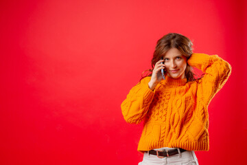 young woman on red background talking on mobile phone